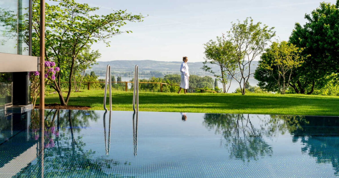 Eine Frau im Bademantel steht am Rande des Pools