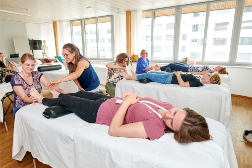 Fussreflexzonen-Massage am Schnuppertag der Heilpraktikerschule Luzern. Füsse von liegenden Personen werden massiert