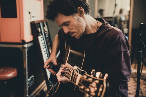 Lovebugs-Frontmann Adrian Sieber spielt sitzend Gitarre