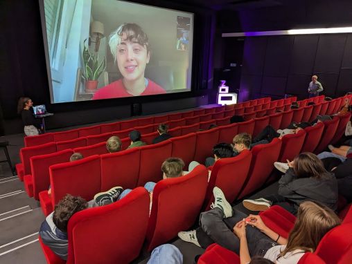 Im Kino Seehof in Zug gucken die Kinder auf die Leinwand, wo ein Videocall mit einer jungen Filmemacherin zu sehen ist.