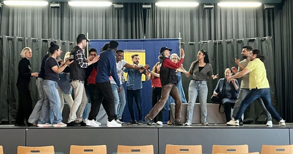 Die Teilnehmerinnen und Teilnehmer von Malaika stehen auf der Bühne, es herrscht ein aufgeregtes Durcheinander.