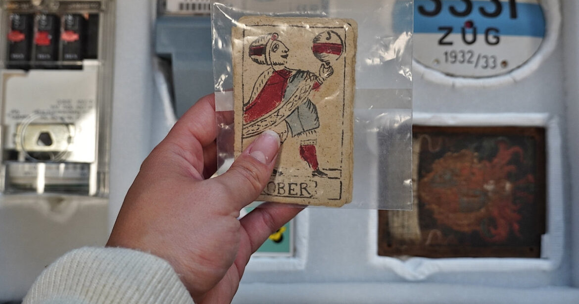 Eine Person hält eine alte Jasskarte in der Hand bei der Handling Collection, Museum Burg Zug