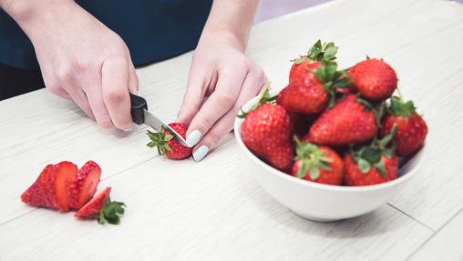 Jemand schneidet Erdbeeren auf dem Tisch.
