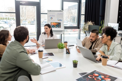 Workshop, Menschen sitzen am Laptop an einem grossen Tisch im Büro