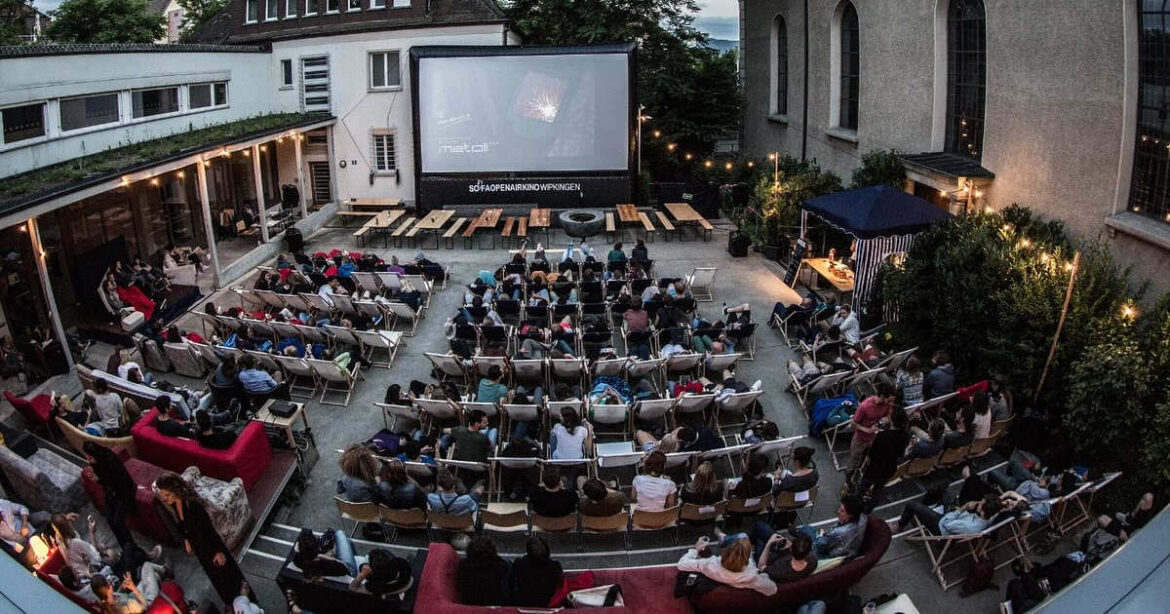 Besucher schauen auf die Leinwand, wo ein Film läuft am Sofaopenairkino Wipkingen
