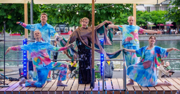Auf einer aufgebauten Bühne an der Reuss singen Theaterschaffende beim Stück baden gehen vom Luzerner Theater