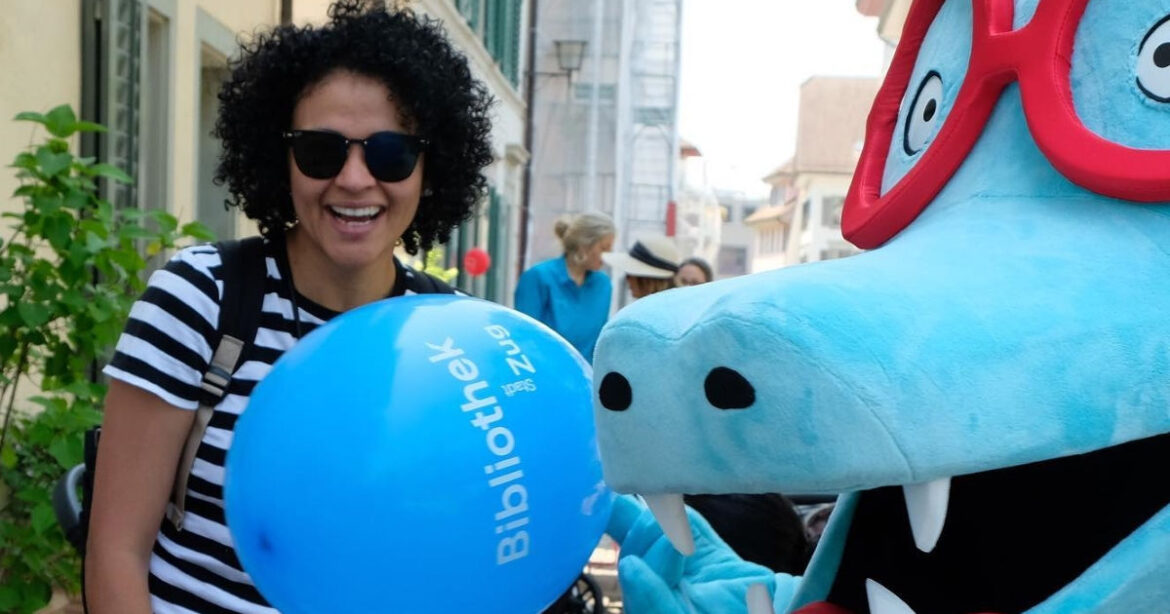 Eine Besucherin freut sich mit dem Maskottchen der Bibliothek Zug am Oswalds-Gassen-Fest