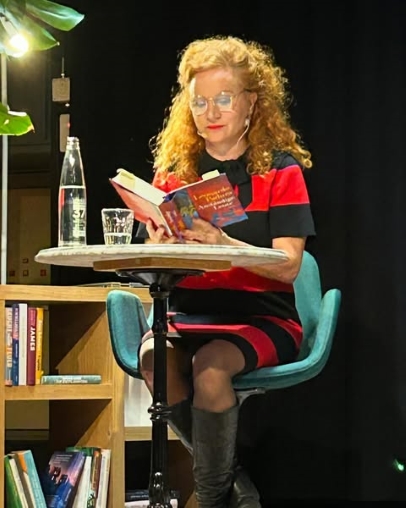 Wanda Wylowa liest an einer Lesung aus einem Buch, sie sitzt am Tisch