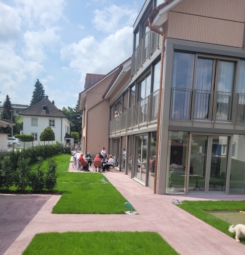 Bild von aussen vom Pflegewohnheim Smaily. Menschen sitzen auf der Terrasse