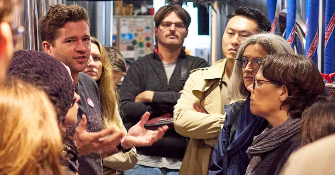 Ein Mann spricht in einem Geschäft, während Umstehende zuhören am Tag der urbanen Produktion in Zürich