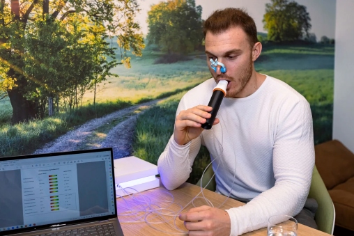 Eine Stoffwechselanalyse wird durchgeführt bei endurance, Mann sitzt dafür an einem Tisch und bläst in ein Gerät