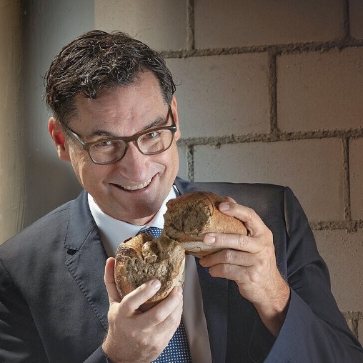 Bäckermeister Michael Kleinert hält ein Brot in den Händen, das er halbiert hat.
