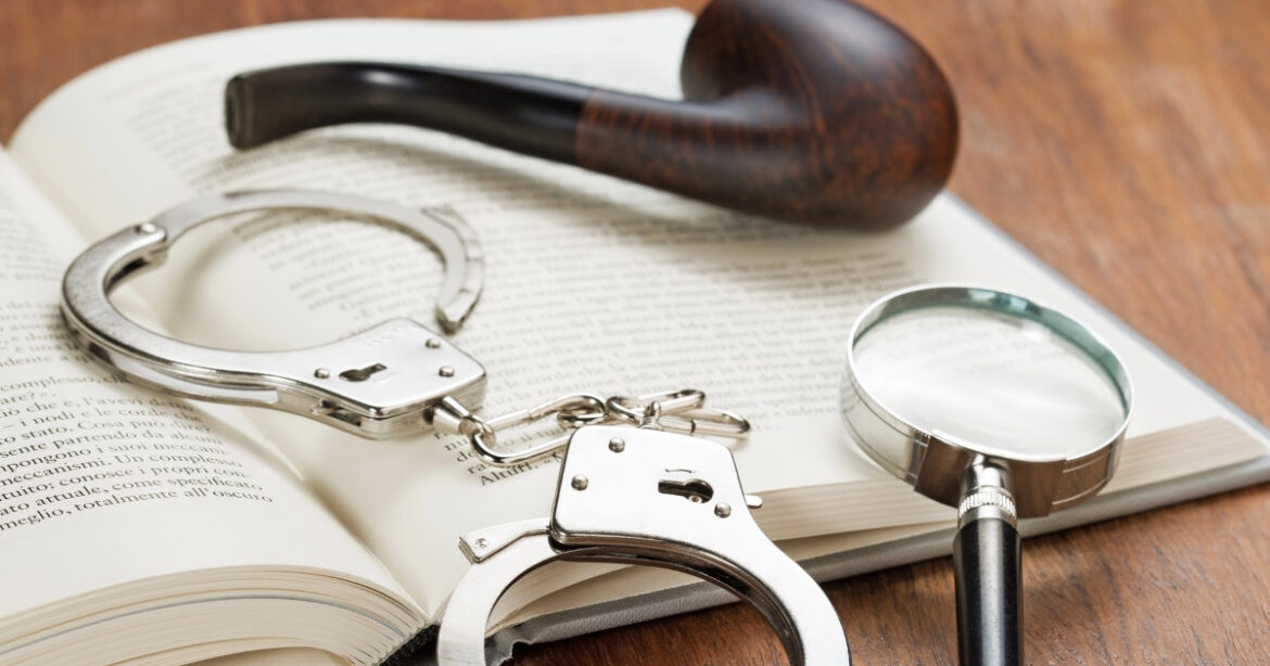 Ein aufgeschlagenes Buch liegt auf dem Tisch, darauf eine Pfeife und Handschellen