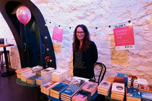 Eine Frau steht hinter Tischen, auf denen Bücher liegen am Literaturfestival Höhenflug im Burgbachkeller