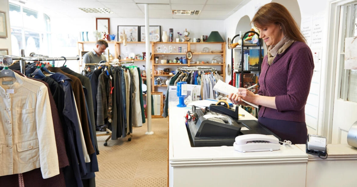 Eine Frau steht an der Kasse hinter der Theke in einem Secondhand-Kleidergeschäft