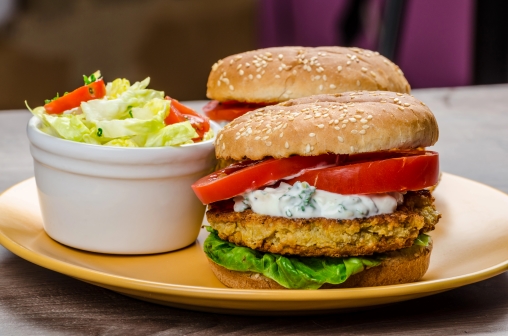 Eine Veggie-Burger und Salat sind auf einem Teller angerichtet
